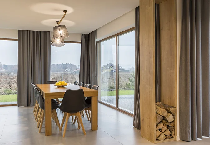 Moderner Essbereich mit großen Fensterflächen, Holztisch und Blick ins Grüne