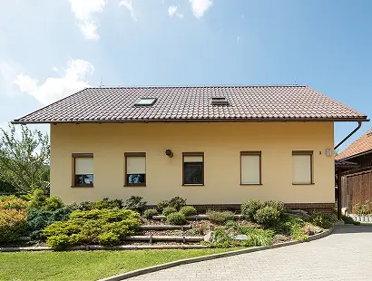 Einfamilienhaus mit geschlossenen Außenrollläden und gepflegtem Vorgarten