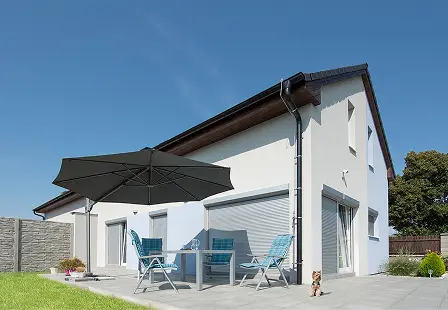 Einfamilienhaus mit Außenrollläden und Terrasse mit Gartenmöbeln