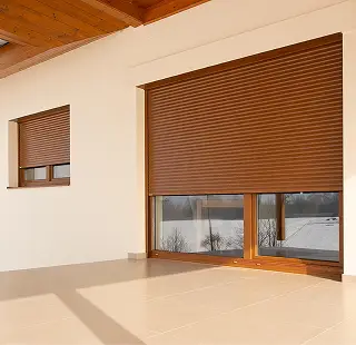 Braune Außenrollläden an den Fenstern eines Hauses mit Blick in verschneite Landschaft