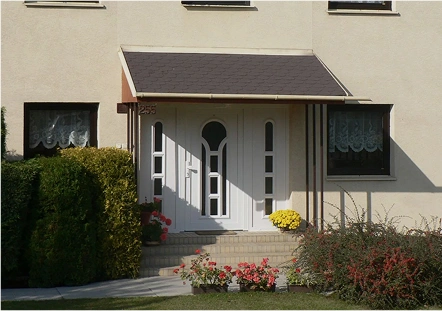 Weiße Haustür mit dekorativer Verglasung und Vordach an einem Einfamilienhaus