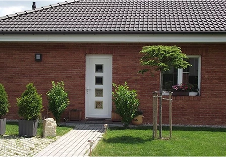 Weiße Haustür mit quadratischen Glasfüllungen an einem Klinkerbungalow